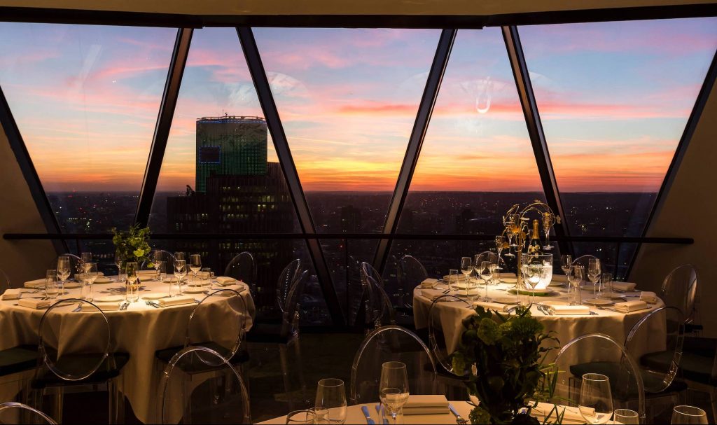 Exclusive hire Level 38 Searcys Gherkin, elegant tables, sunset view for corporate events.