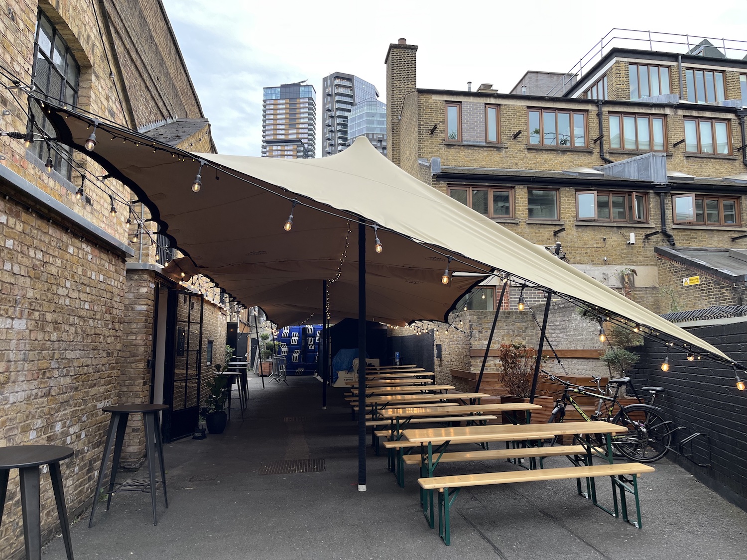 Versatile outdoor event space with stylish tent and communal tables in Shoreditch Studios.