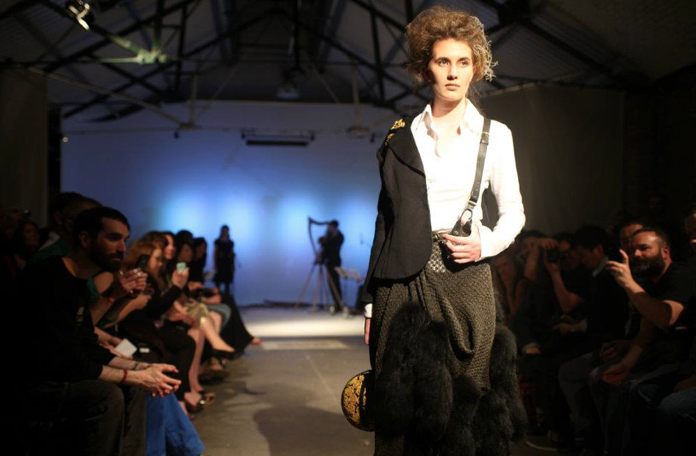 Dynamic fashion runway in Shoreditch Studios with industrial backdrop and focused audience.
