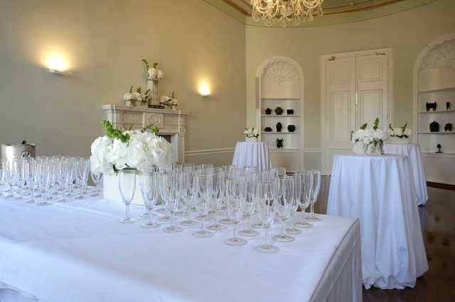 Elegant event space with white tables and floral centerpieces for receptions or gatherings.
