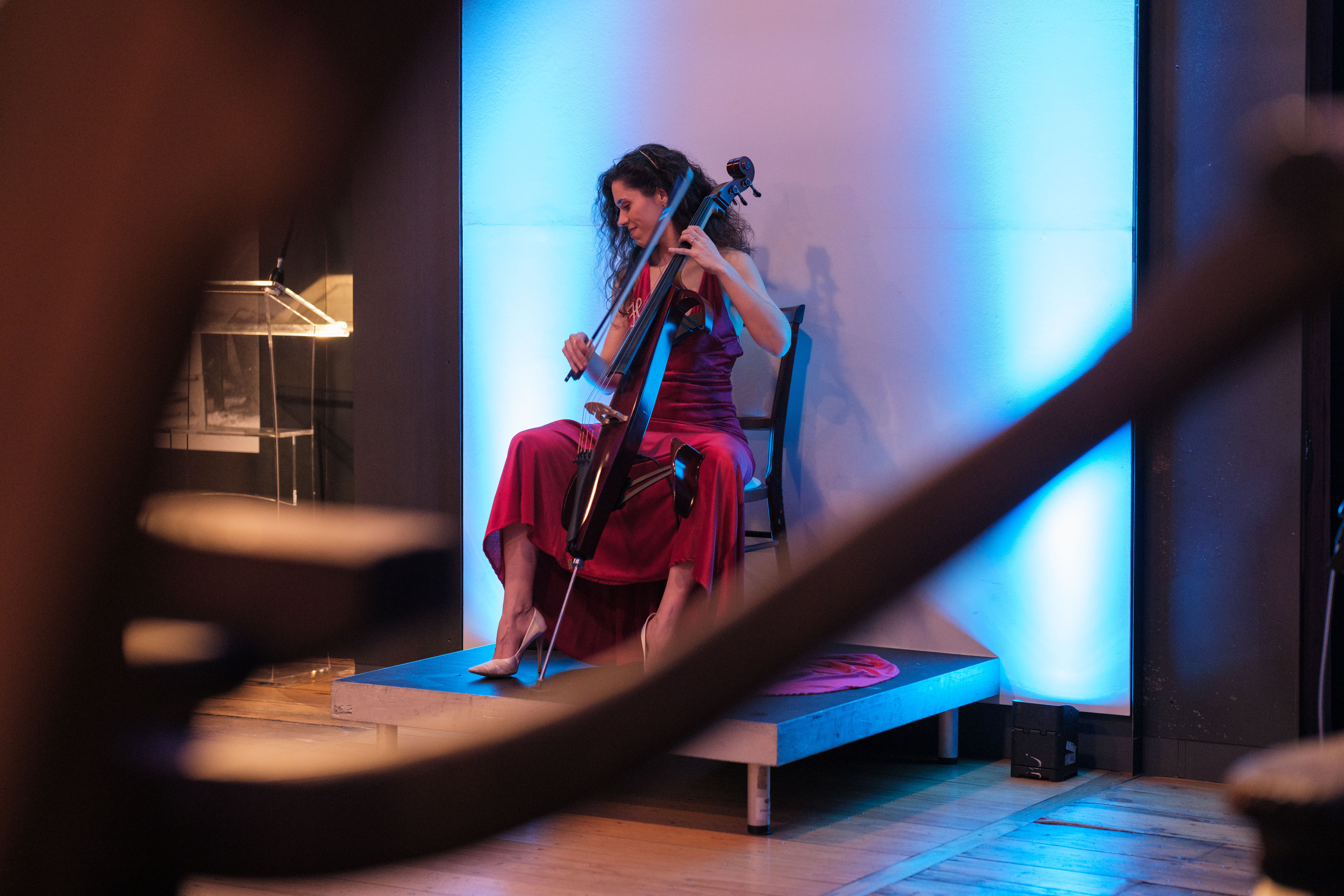 Cellist performing on stage at London Museum Docklands event with blue lighting.