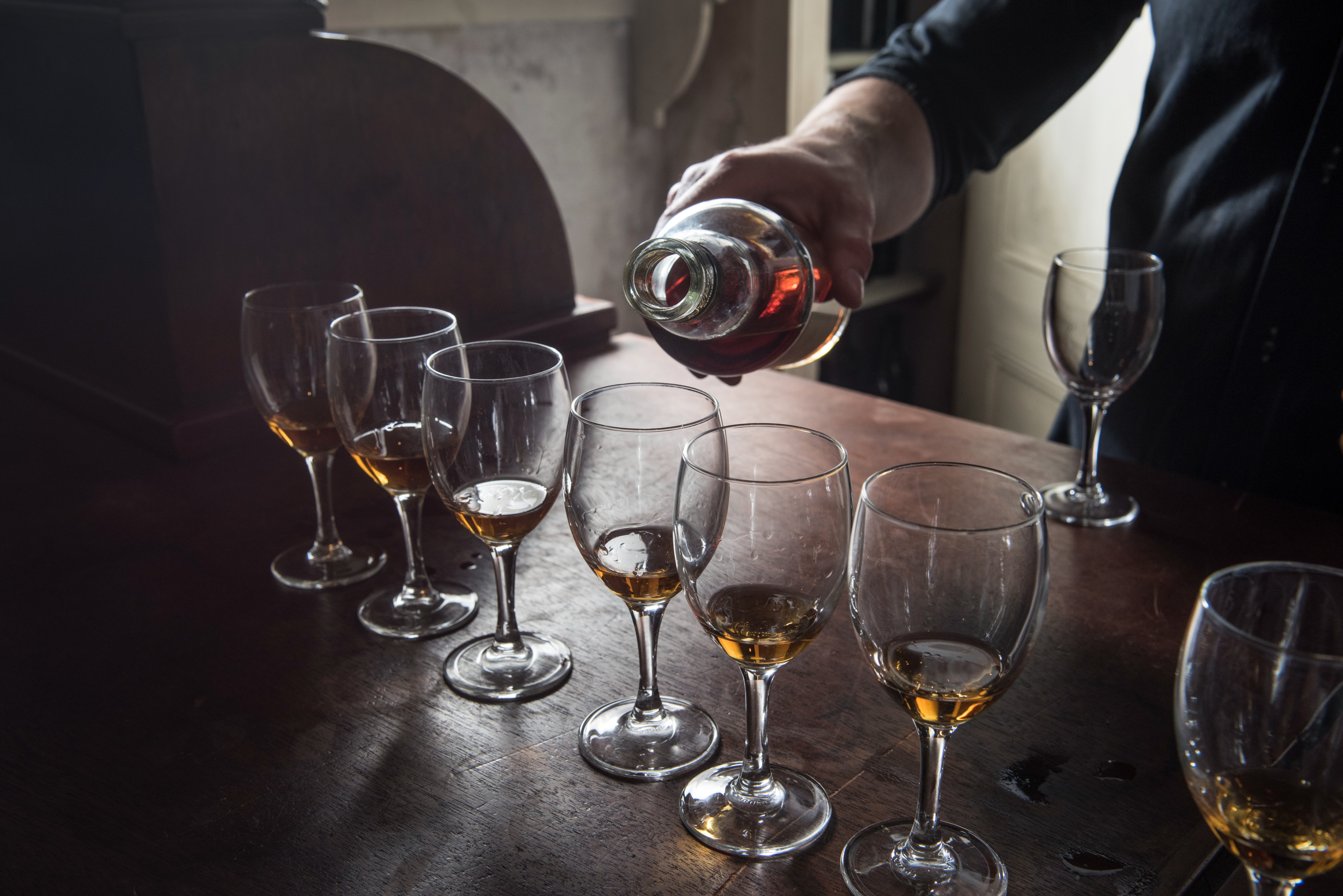 Professional pouring amber liquid at upscale tasting event in Sailortown Gallery, London.