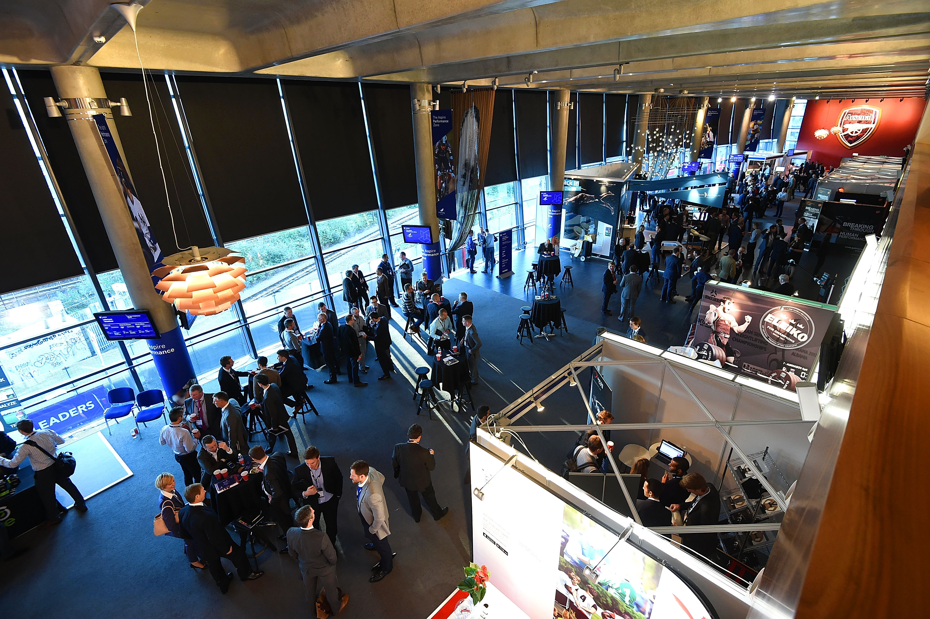 Woolwich Emirates Stadium trade show with attendees networking and modern displays.