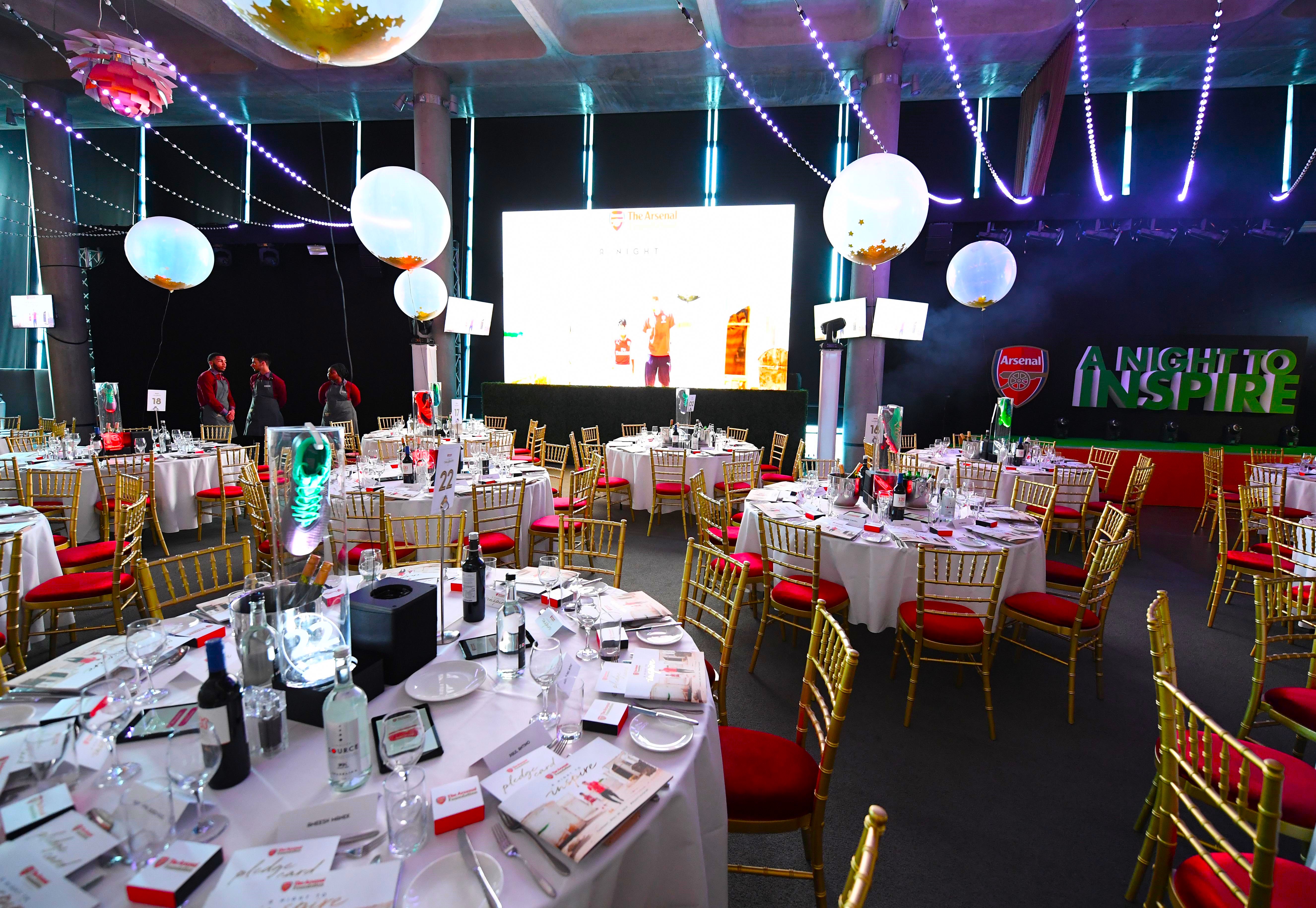 Elegant dinner setup at Emirates Stadium with gold chairs and vibrant decor.