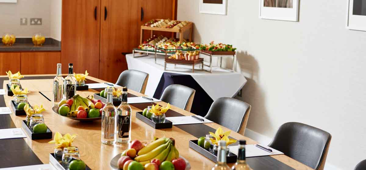 Meeting room setup at The Lowry Hotel with fresh fruit centerpieces and snacks.