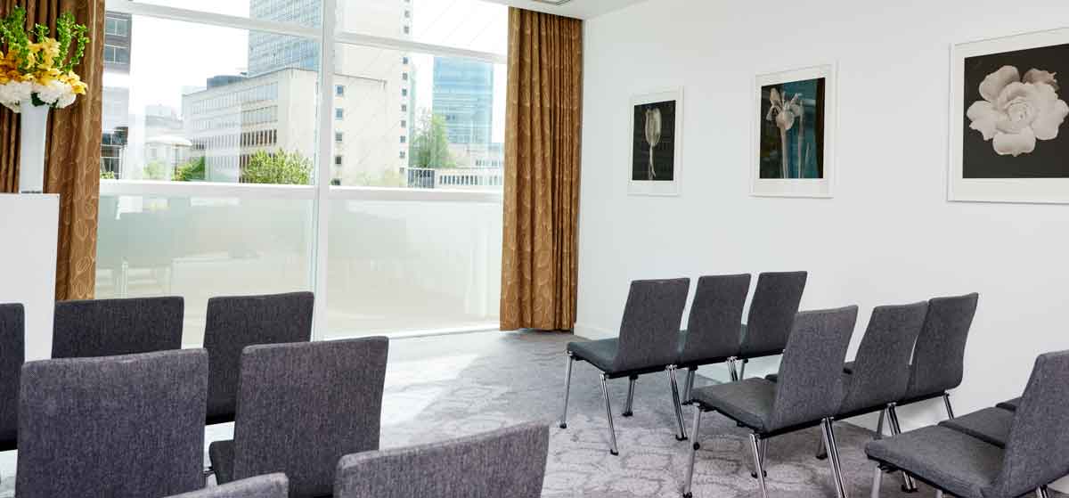 Modern meeting room with gray chairs and natural light at The Lowry Hotel.