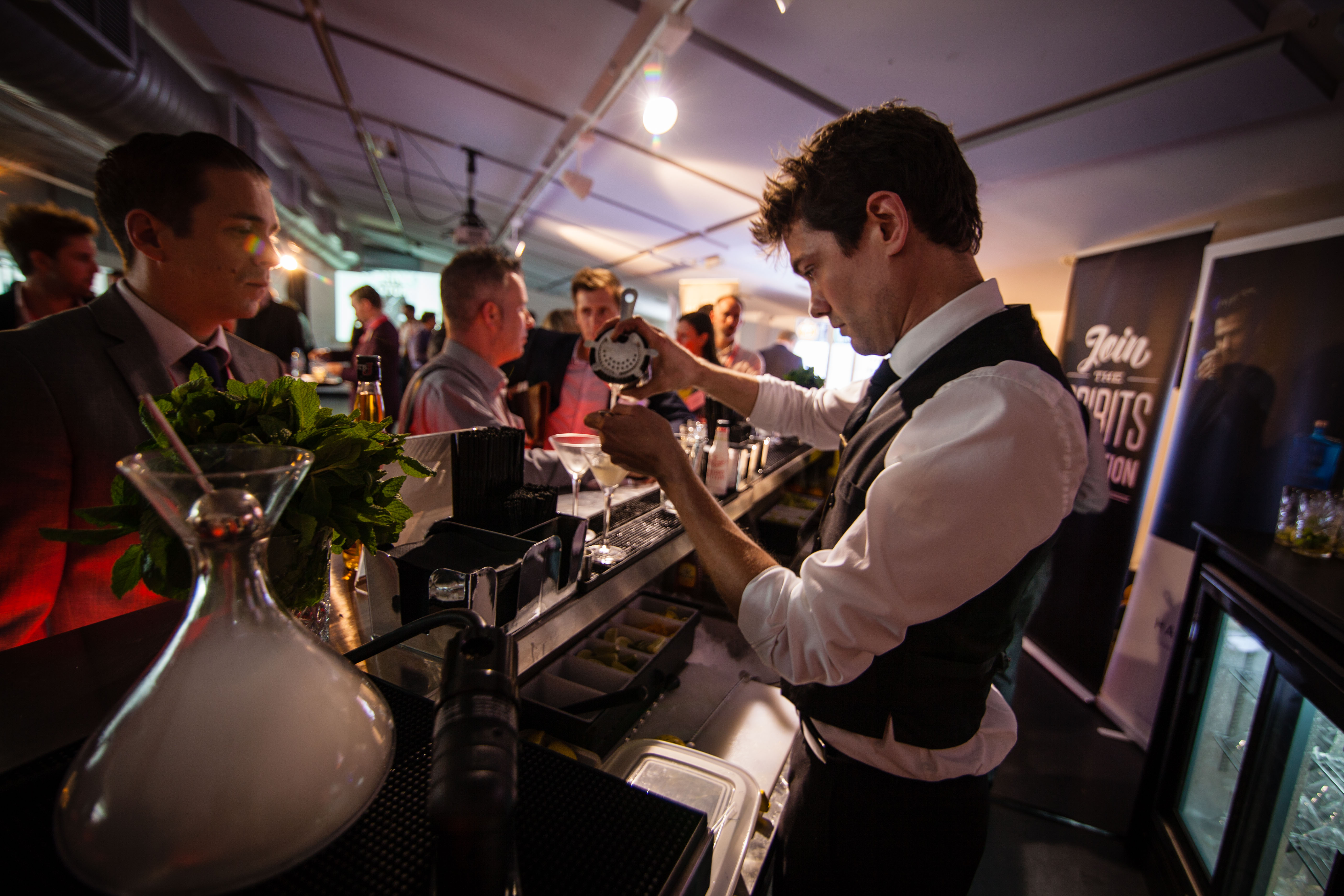 Skilled bartender crafting cocktails at a lively networking event bar in Rich Mix.