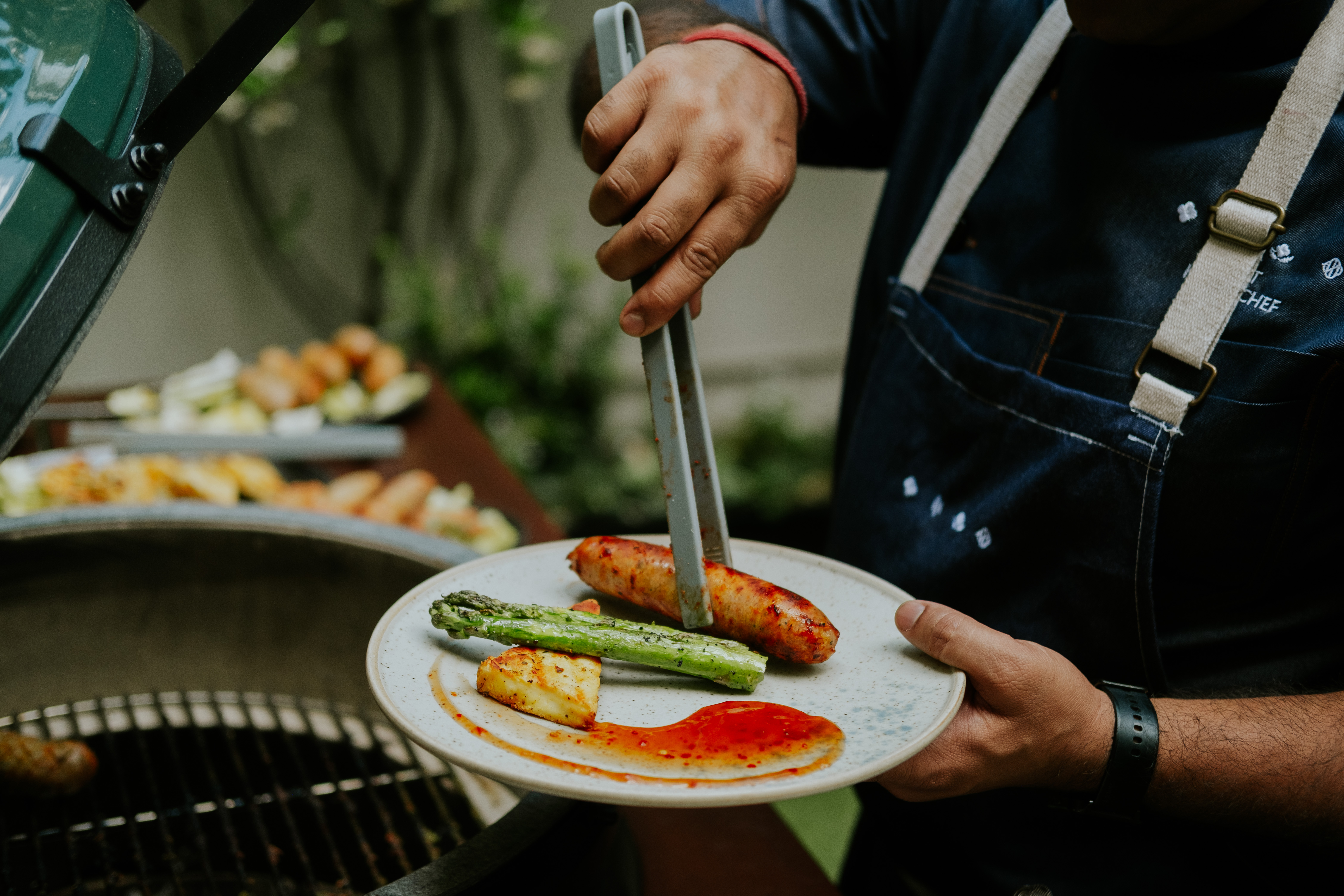 Chef plating grilled food at The Hyde Garden, Roseate House London for event catering.
