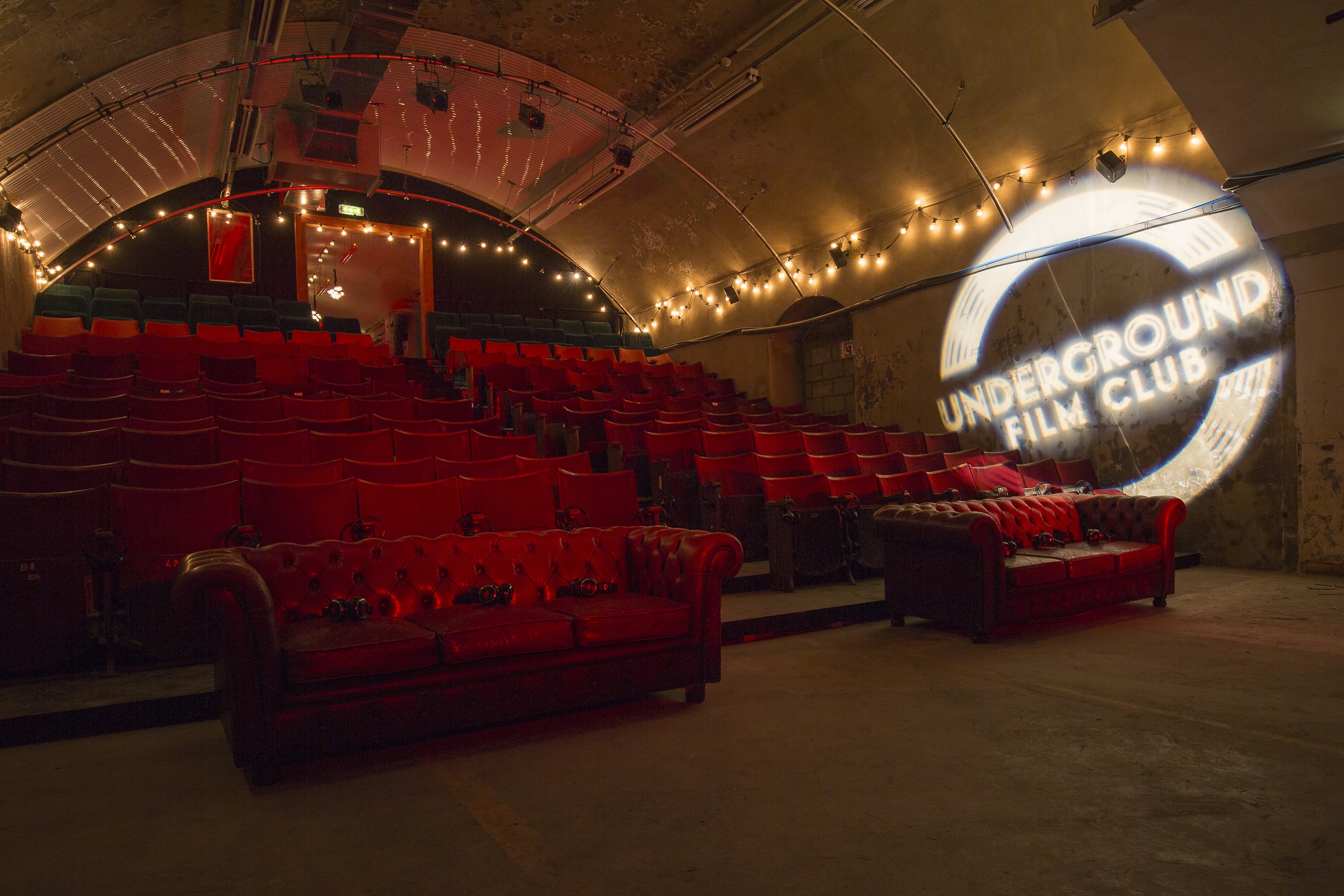 "Cozy underground venue with red seating for intimate film screenings and events."