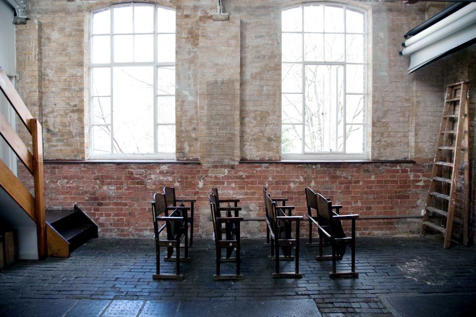 Minimalist event space with wooden chairs and natural light, perfect for workshops and gatherings.