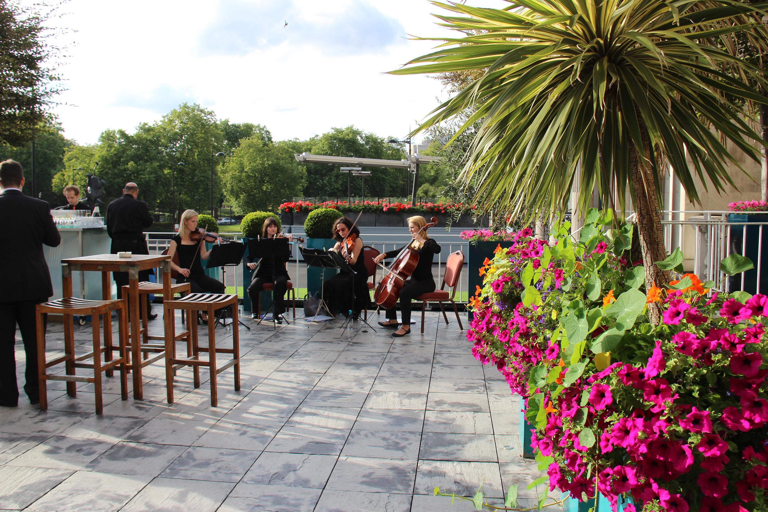 Elegant outdoor corporate event at Argyll Room with string quartet and lush greenery.