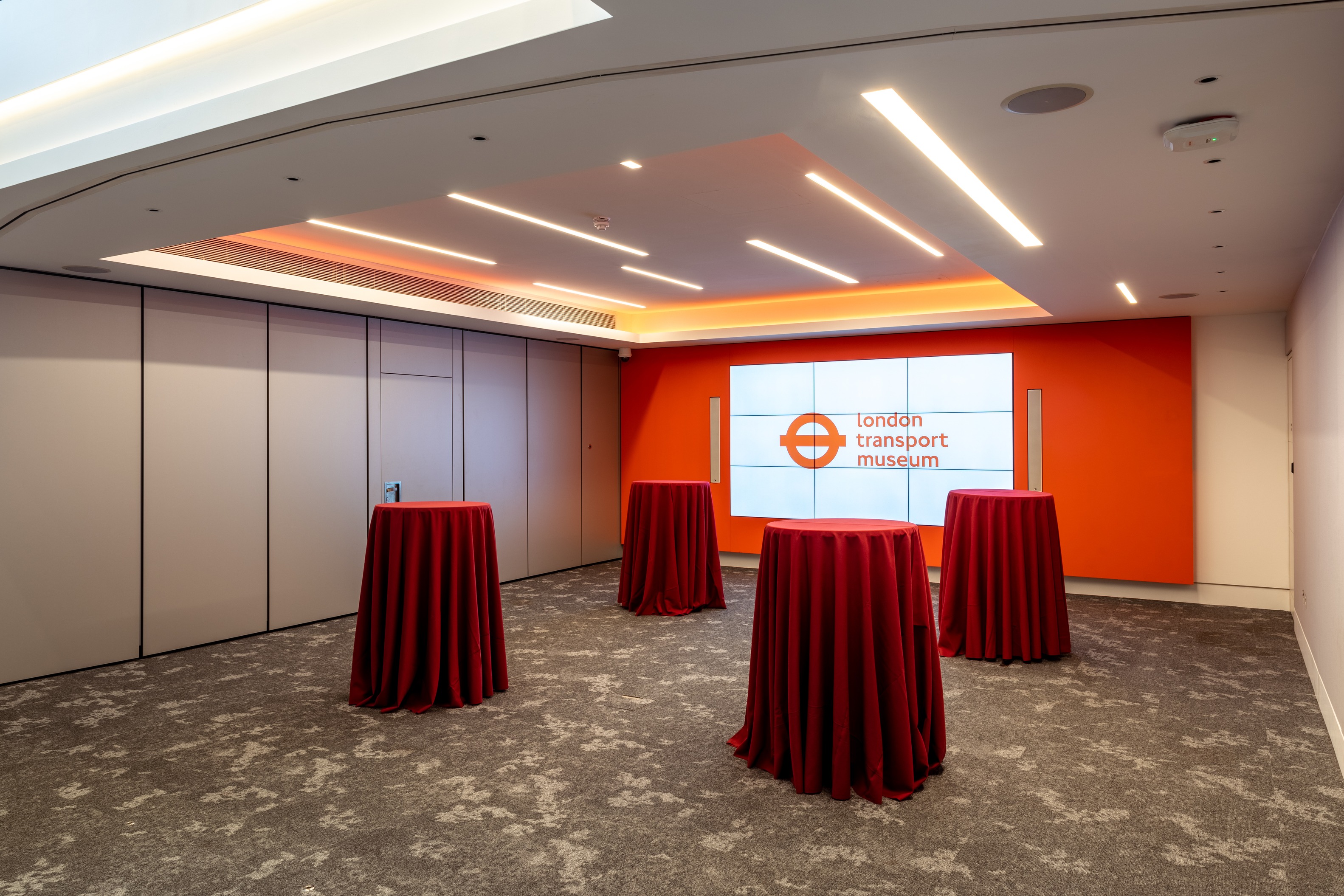 Cubic Theatre at London Transport Museum, modern event space with red tablecloths.