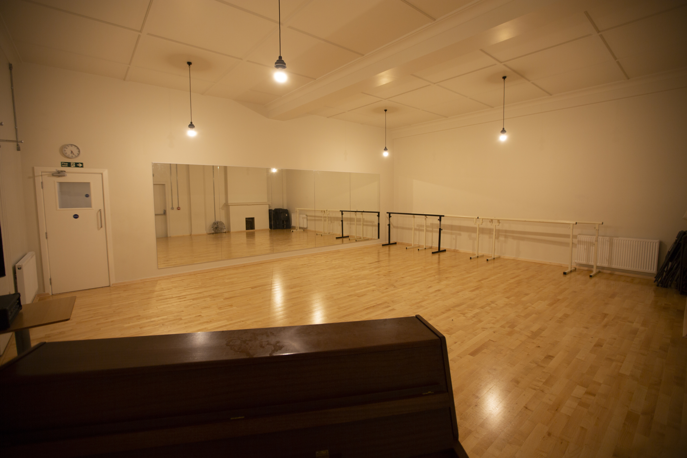 Spacious dance studio with wooden floors for workshops and fitness classes.