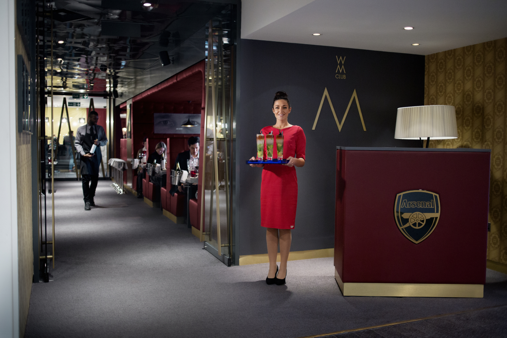 M Club at Emirates Stadium: elegant event space with staff in red dress, ideal for meetings.