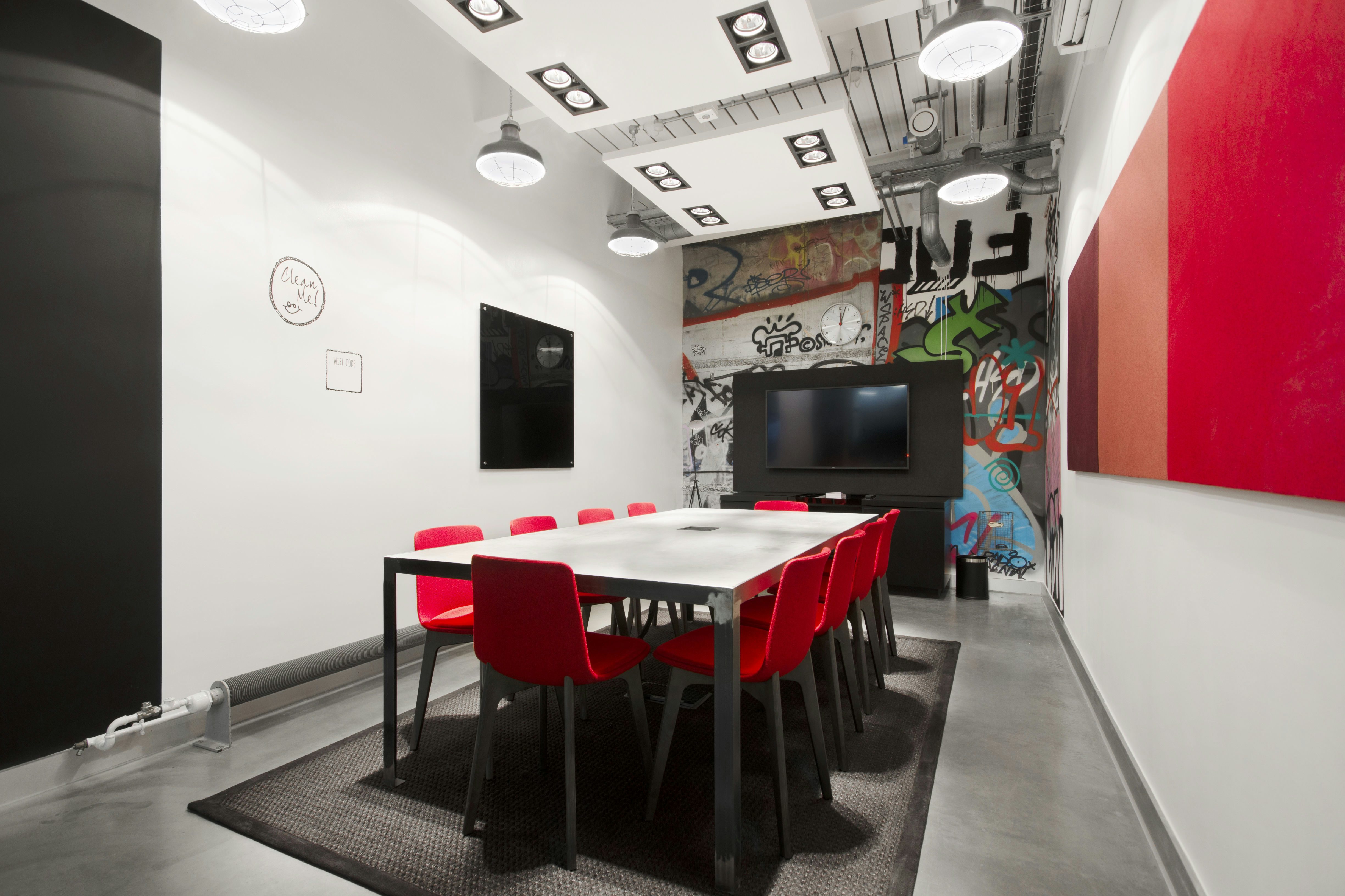 Modern meeting room with sleek table, red chairs, ideal for collaboration and presentations.