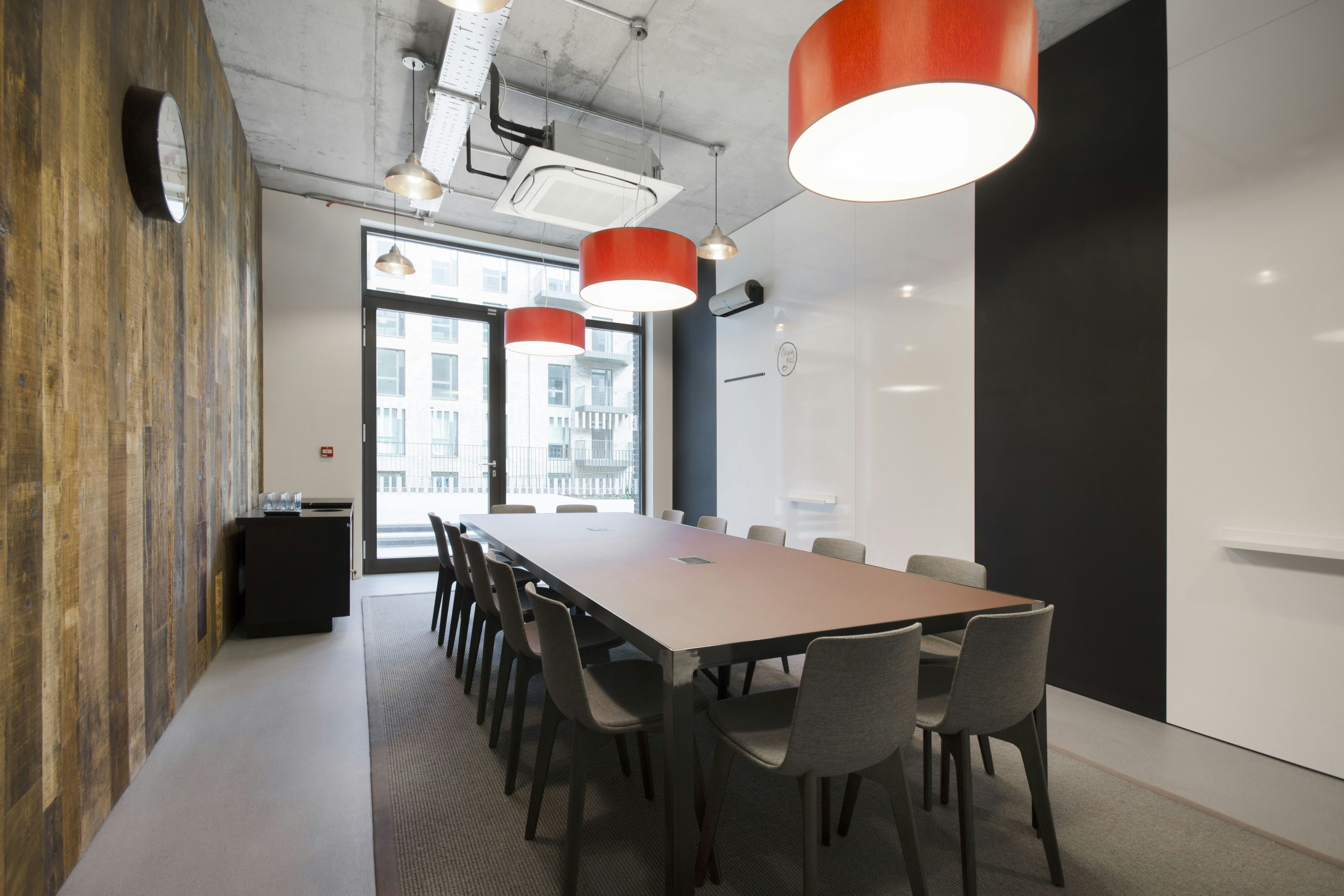 Modern meeting room with long table, warm wood accents for workshops and discussions.