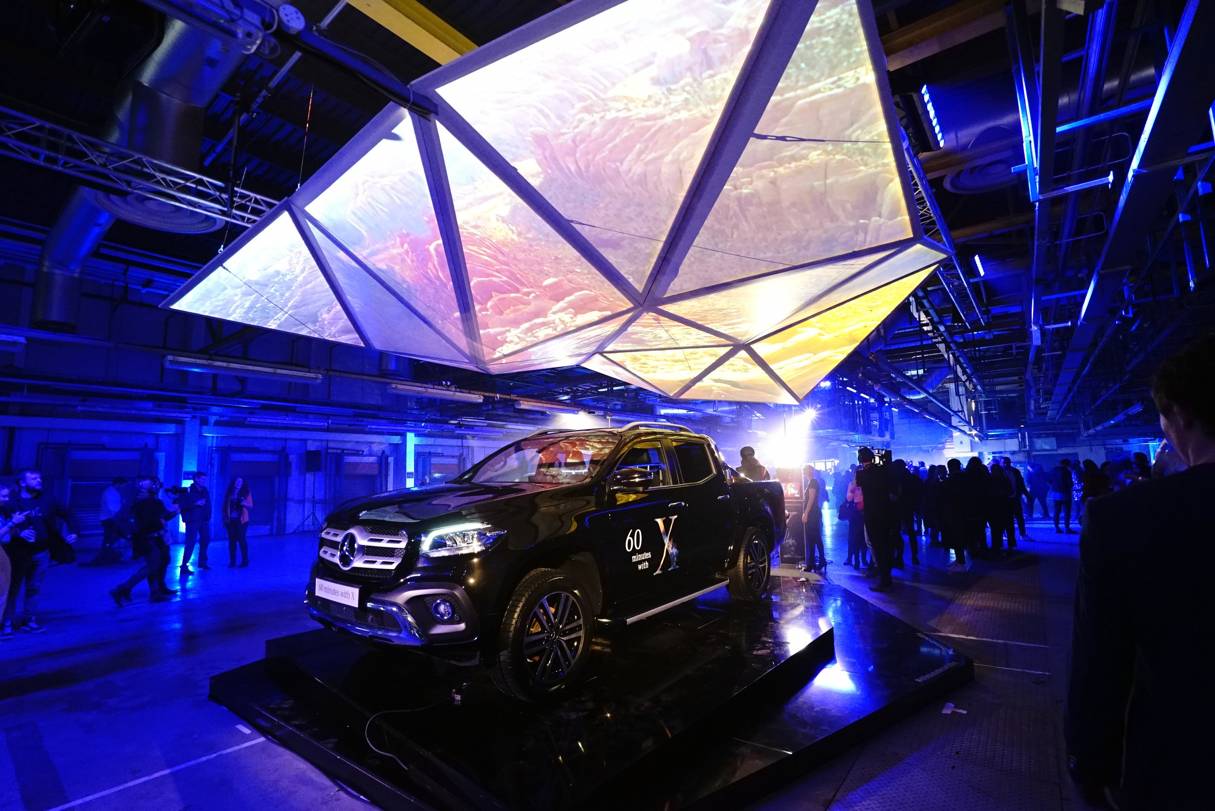 Dynamic event space with vehicle display and geometric projection for product launches.