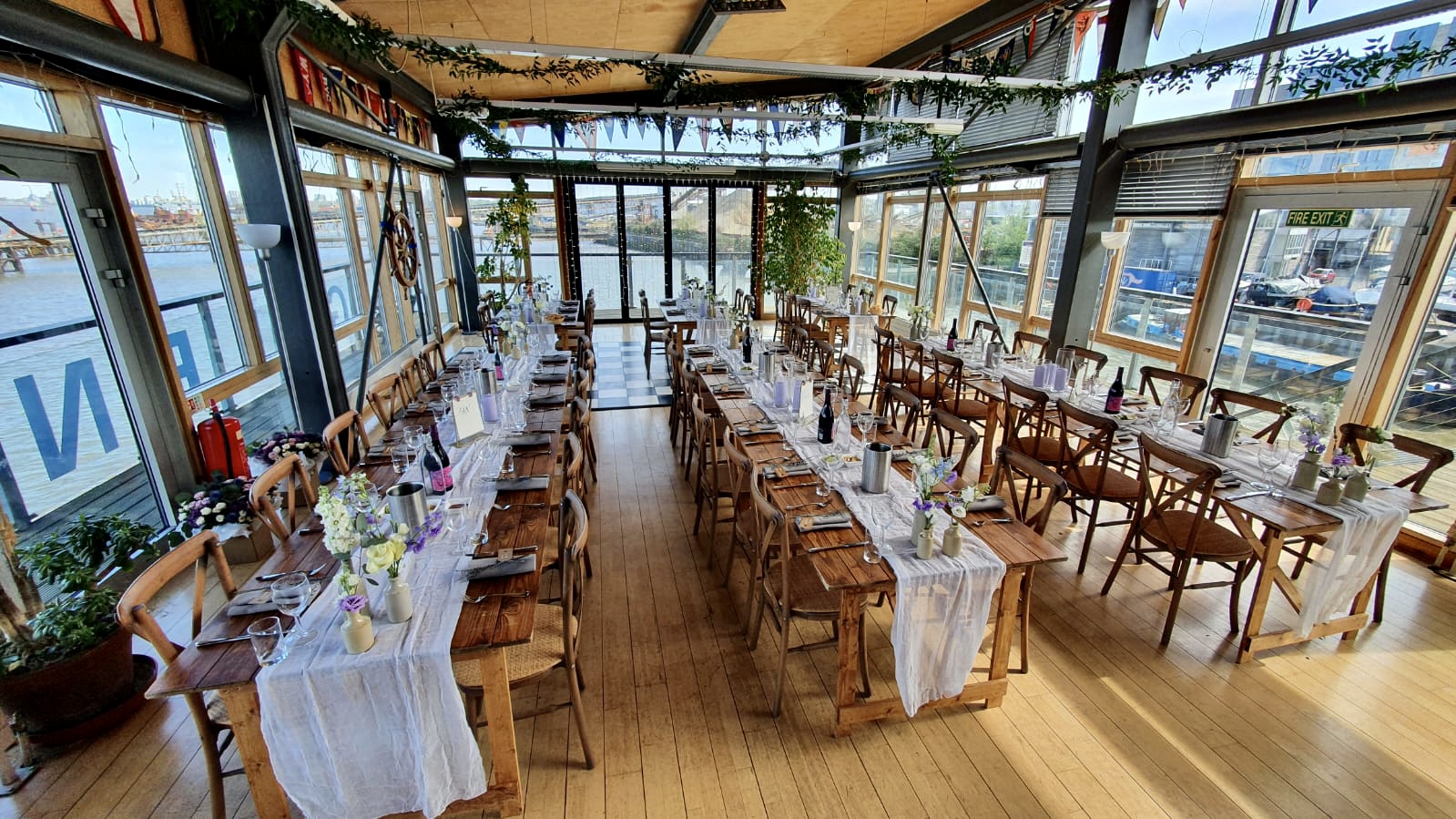 Elegant event space at Greenwich Yacht Club with floral centerpieces and waterfront view.