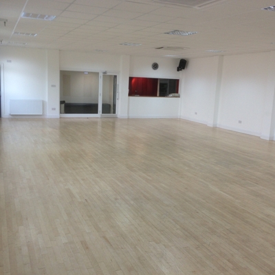 Spacious event space with light wood flooring, ideal for workshops and gatherings.