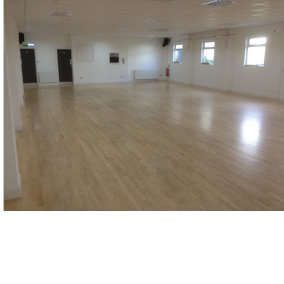 Spacious event space with polished wooden floors, ideal for meetings and workshops.