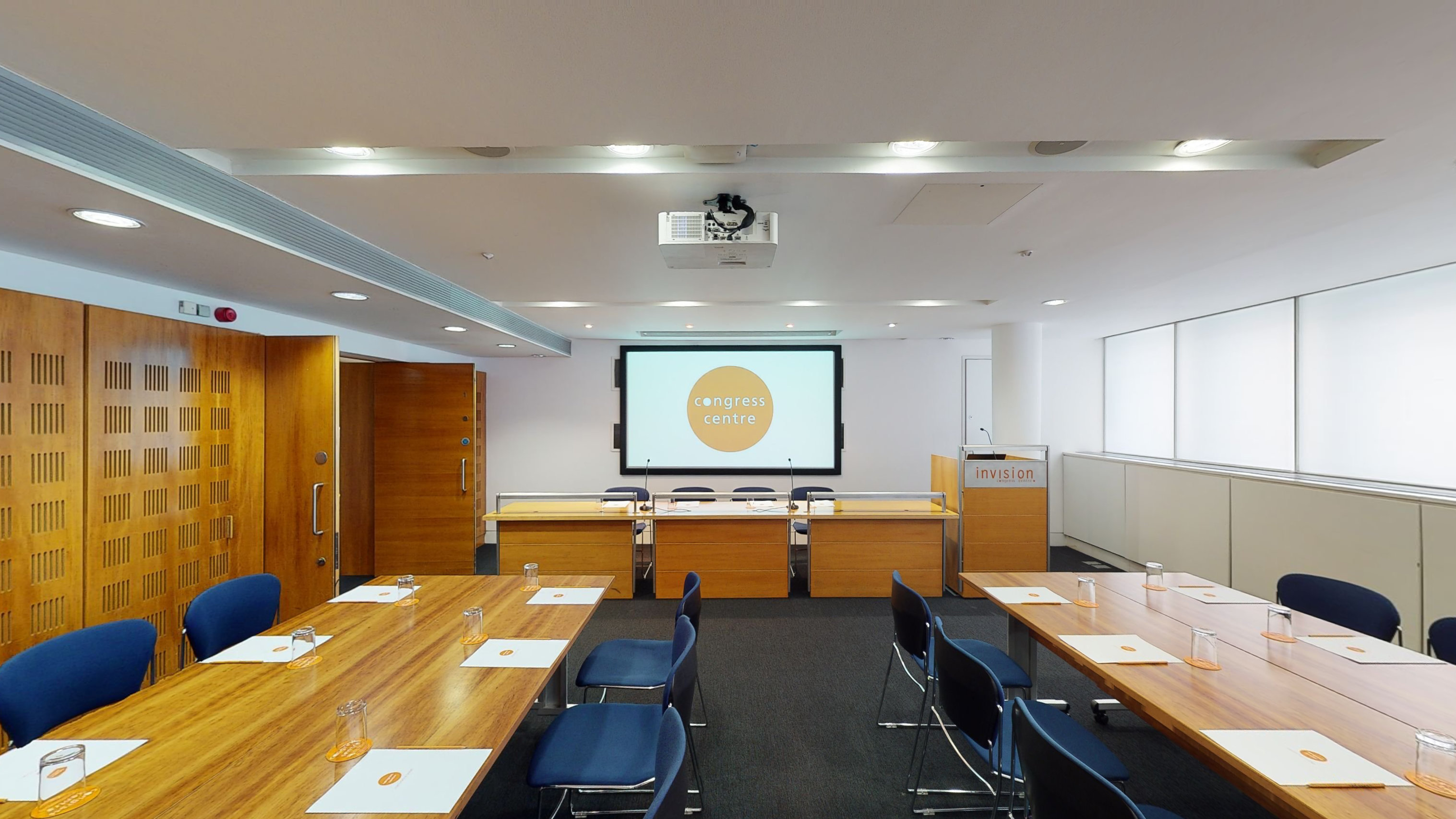 Modern meeting room with wooden table and projector screen at Congress Centre.