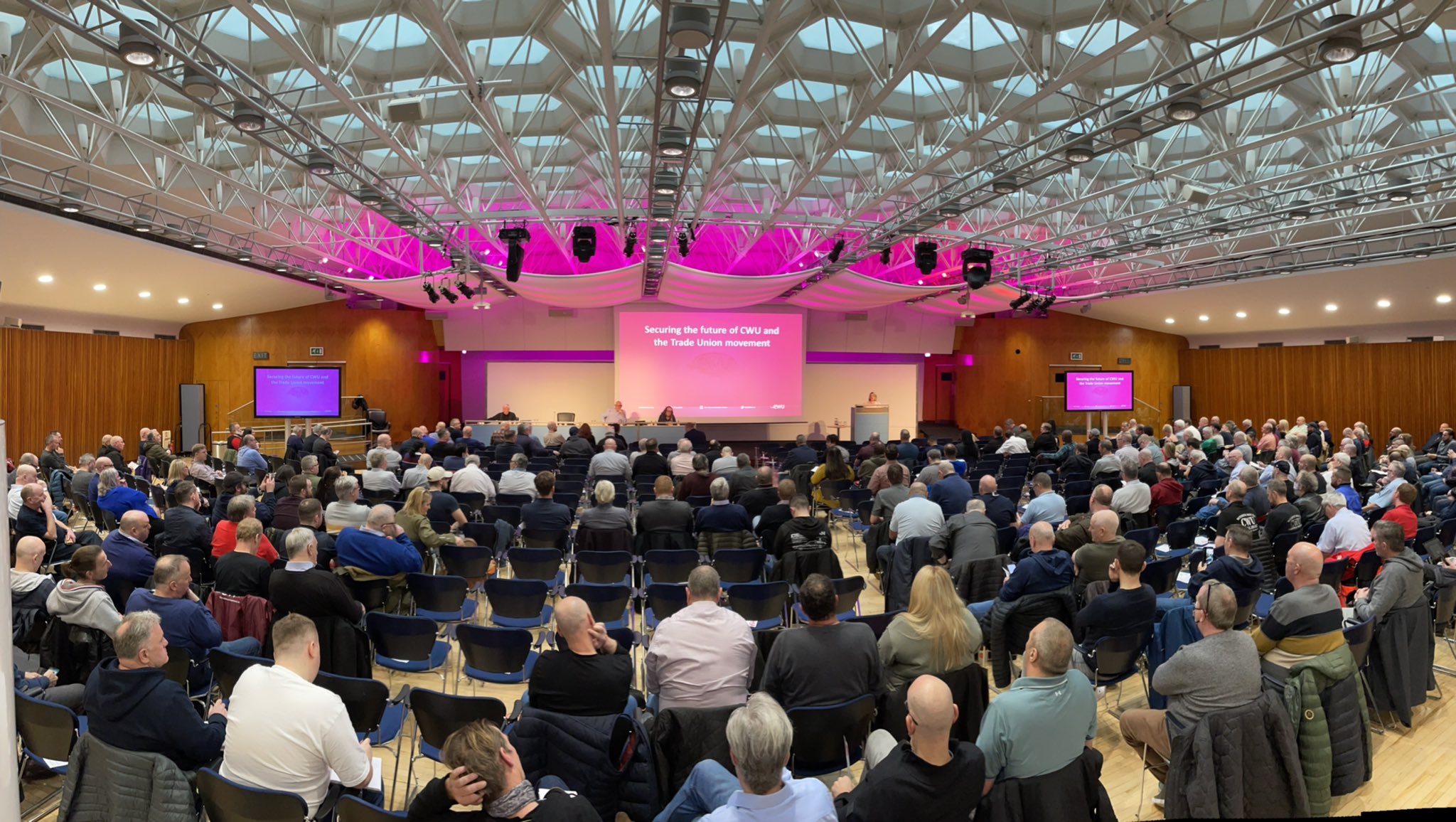 Congress Hall conference with engaging speaker, modern AV tech, and vibrant pink lighting.