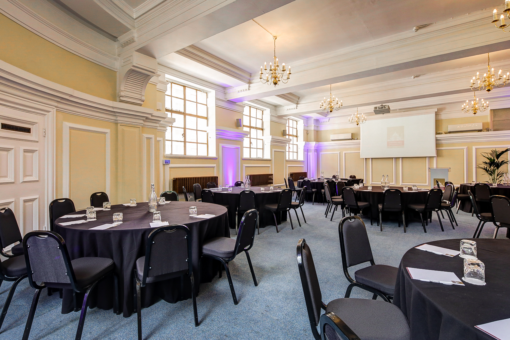 George Thomas in Central Hall Westminster, elegant event space with round tables and uplighting.