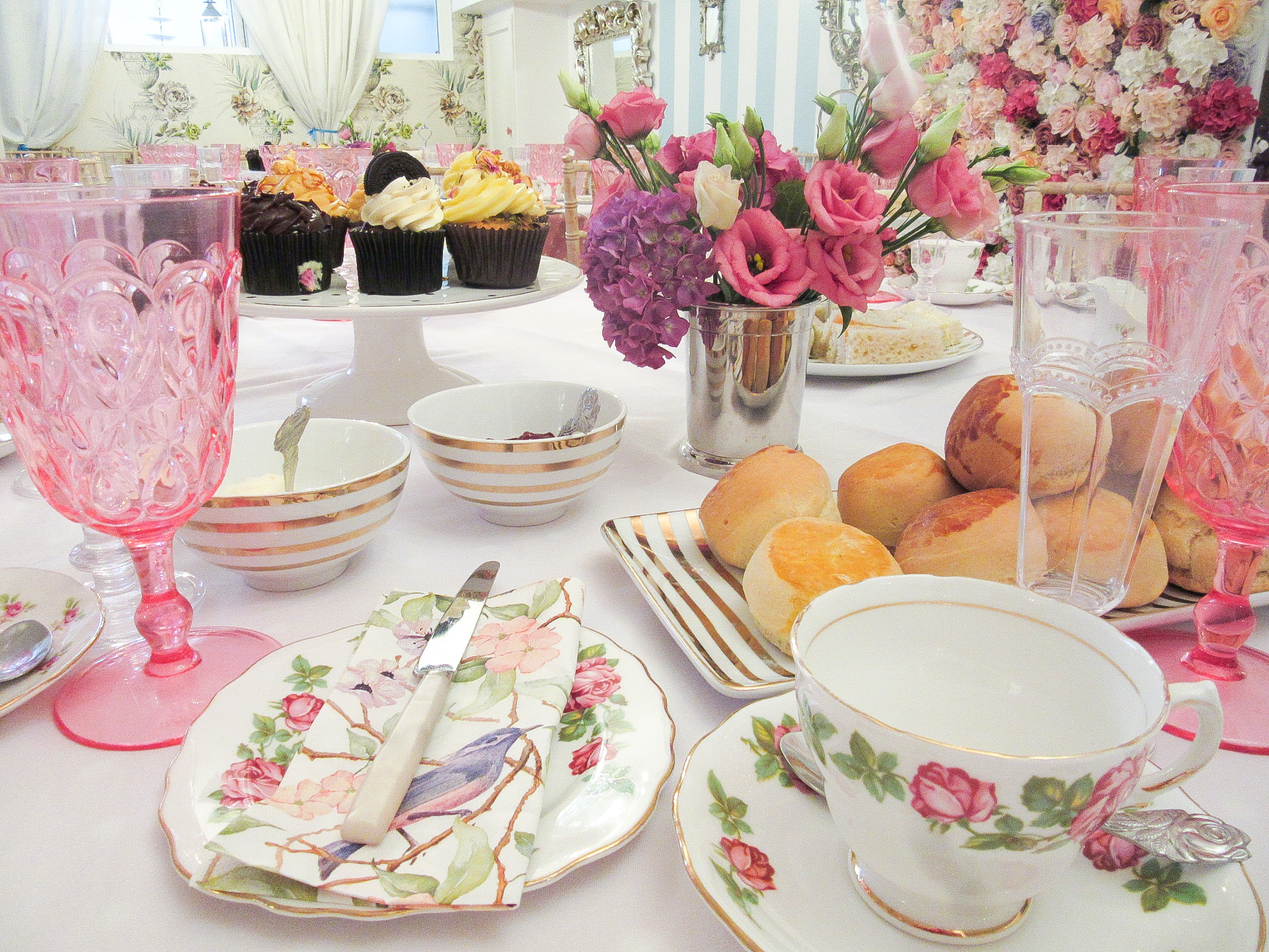 Elegant tea party table with delicate china and vibrant flowers for high-end events.