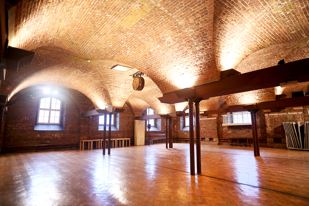 Spacious event venue with brick arch ceiling, perfect for corporate meetings and gatherings.