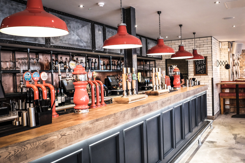 Stylish bar venue with red pendant lights for networking events and social gatherings.