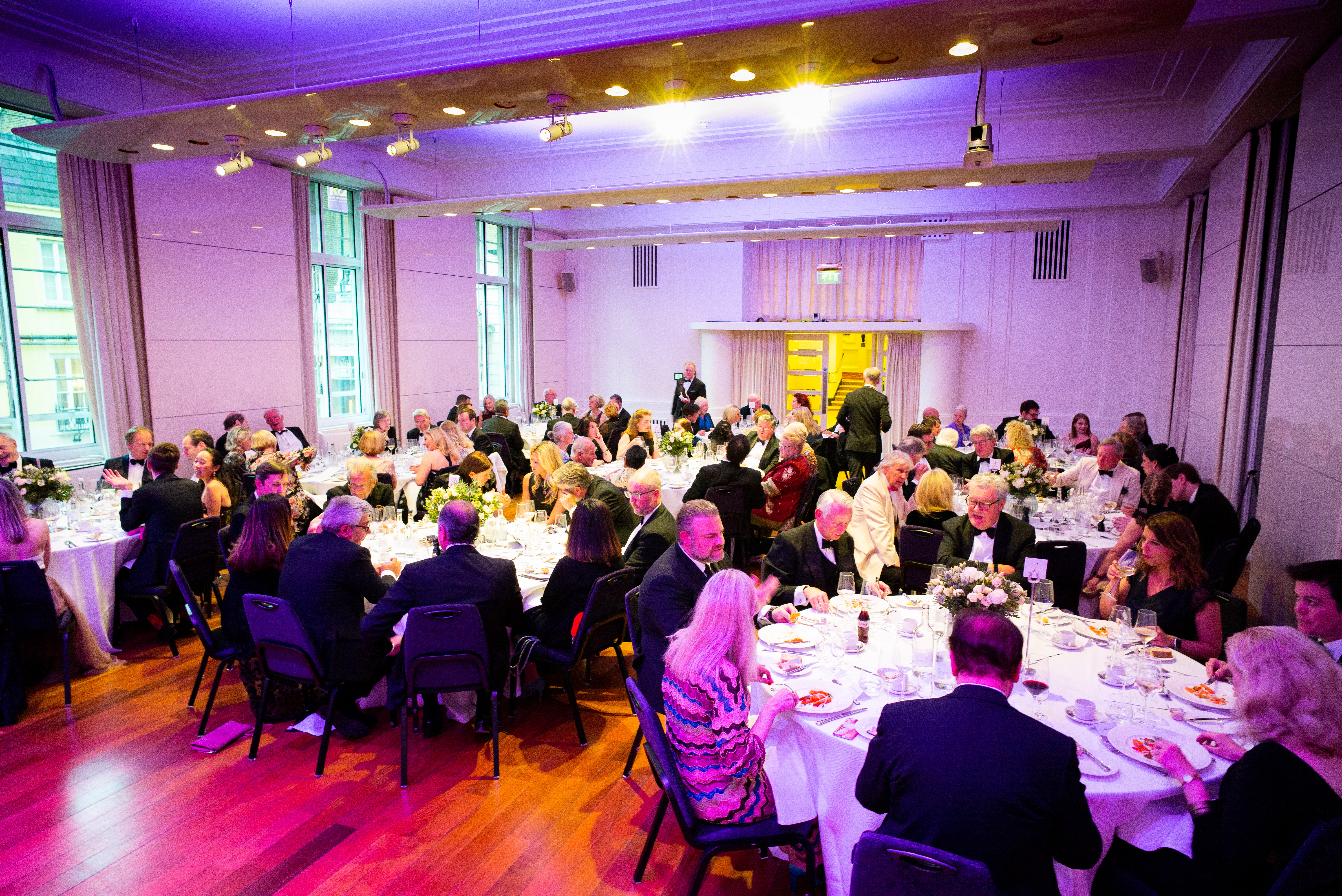 Gala dinner in Princess Alexandra Hall, featuring elegant round tables and vibrant atmosphere.