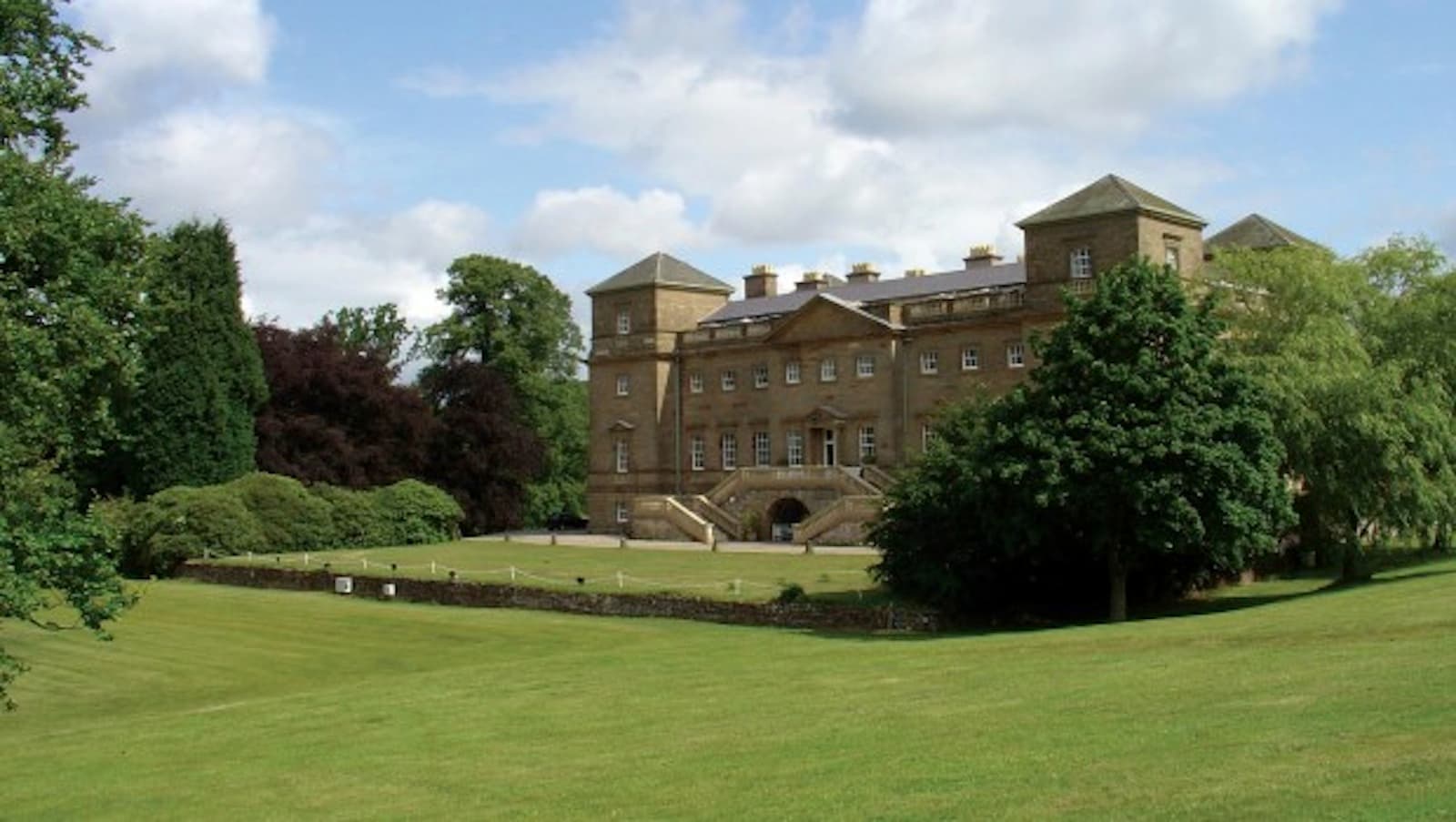 Grand White Hall venue for corporate retreats and elegant events, surrounded by lush greenery.