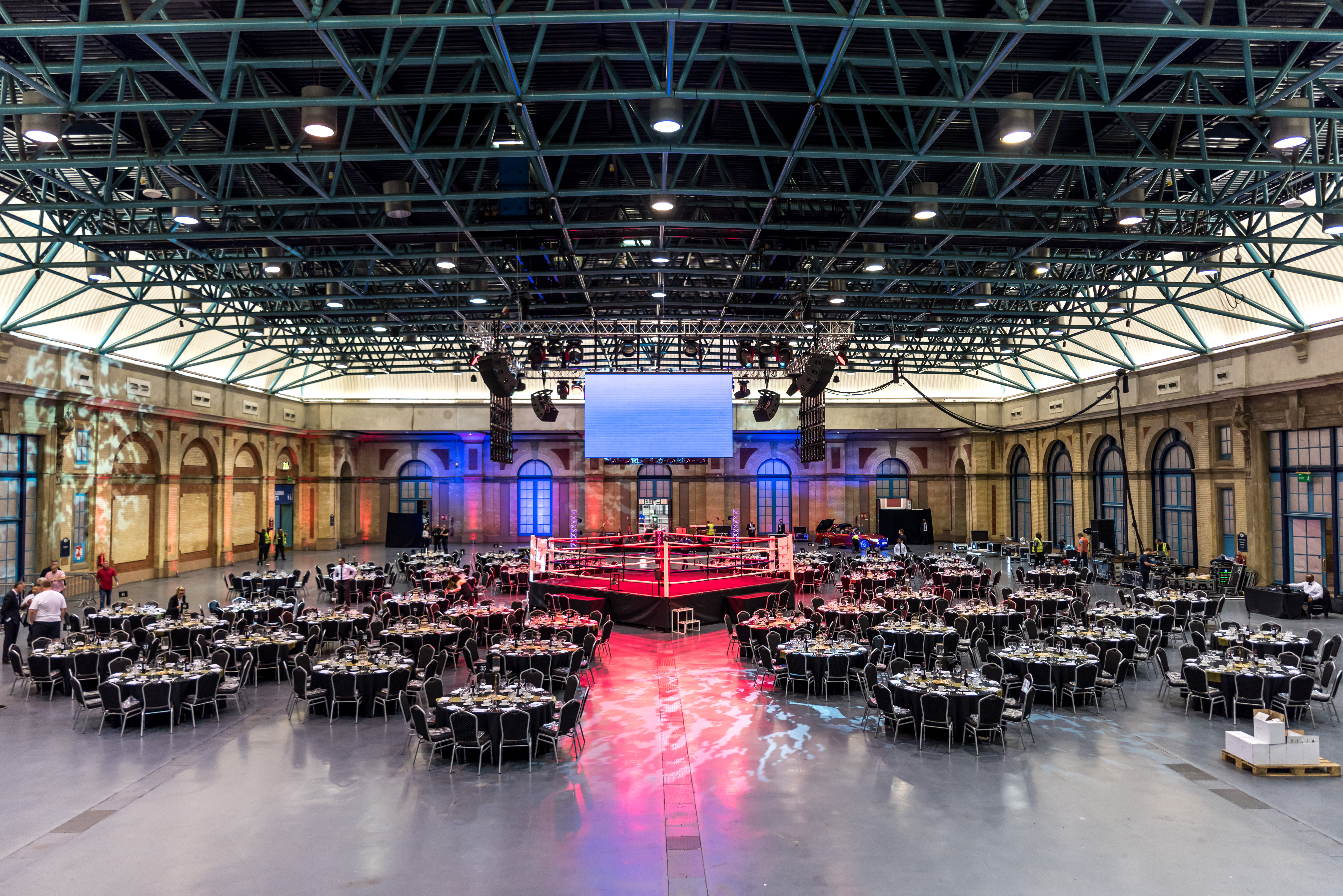 West Hall at Alexandra Palace set for a gala with round tables and boxing ring.