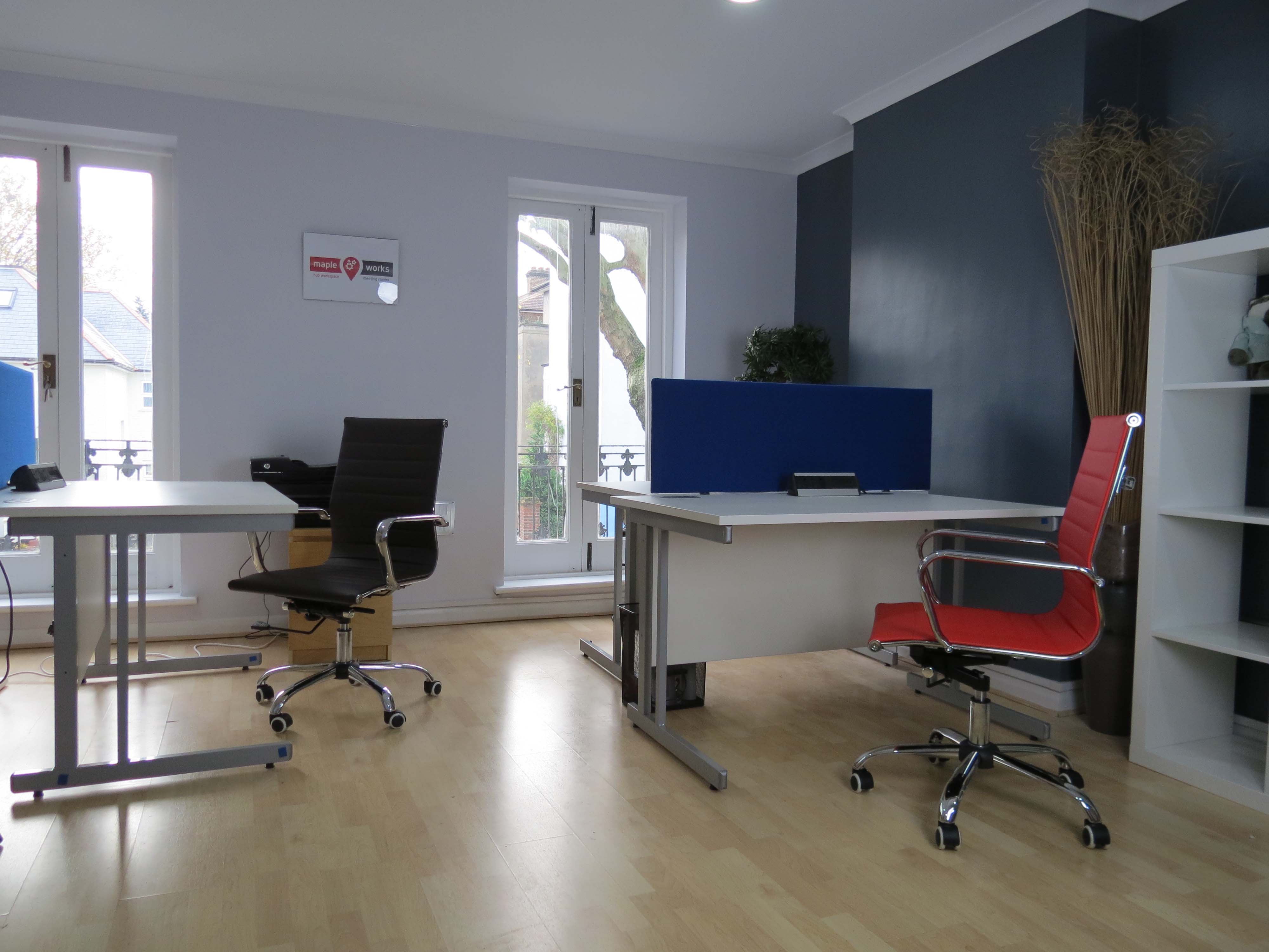 Modern shared workspace with red chair, ideal for meetings and brainstorming sessions.