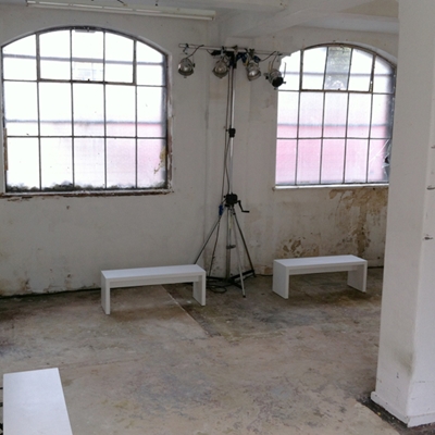 Minimalist shared workspace with white benches, ideal for creative events and workshops.