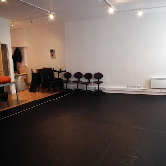 Versatile rehearsal space with black flooring for workshops and fitness classes.