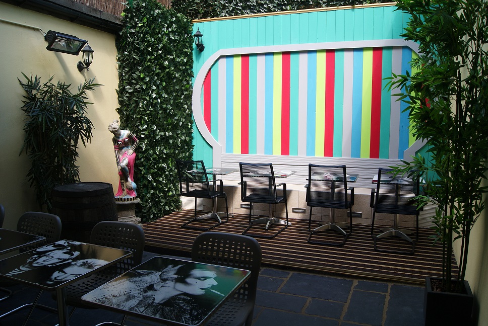Vibrant outdoor lounge bar with colorful backdrop, ideal for social gatherings and events.