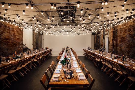 Elegant dinner setup in Shoreditch Studios with string lights, perfect for events.