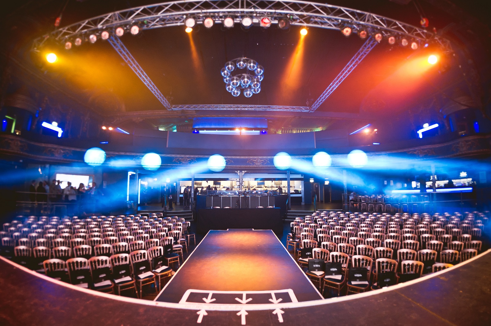 Electric Brixton event space with stage, chairs, and elegant chandelier for conferences.