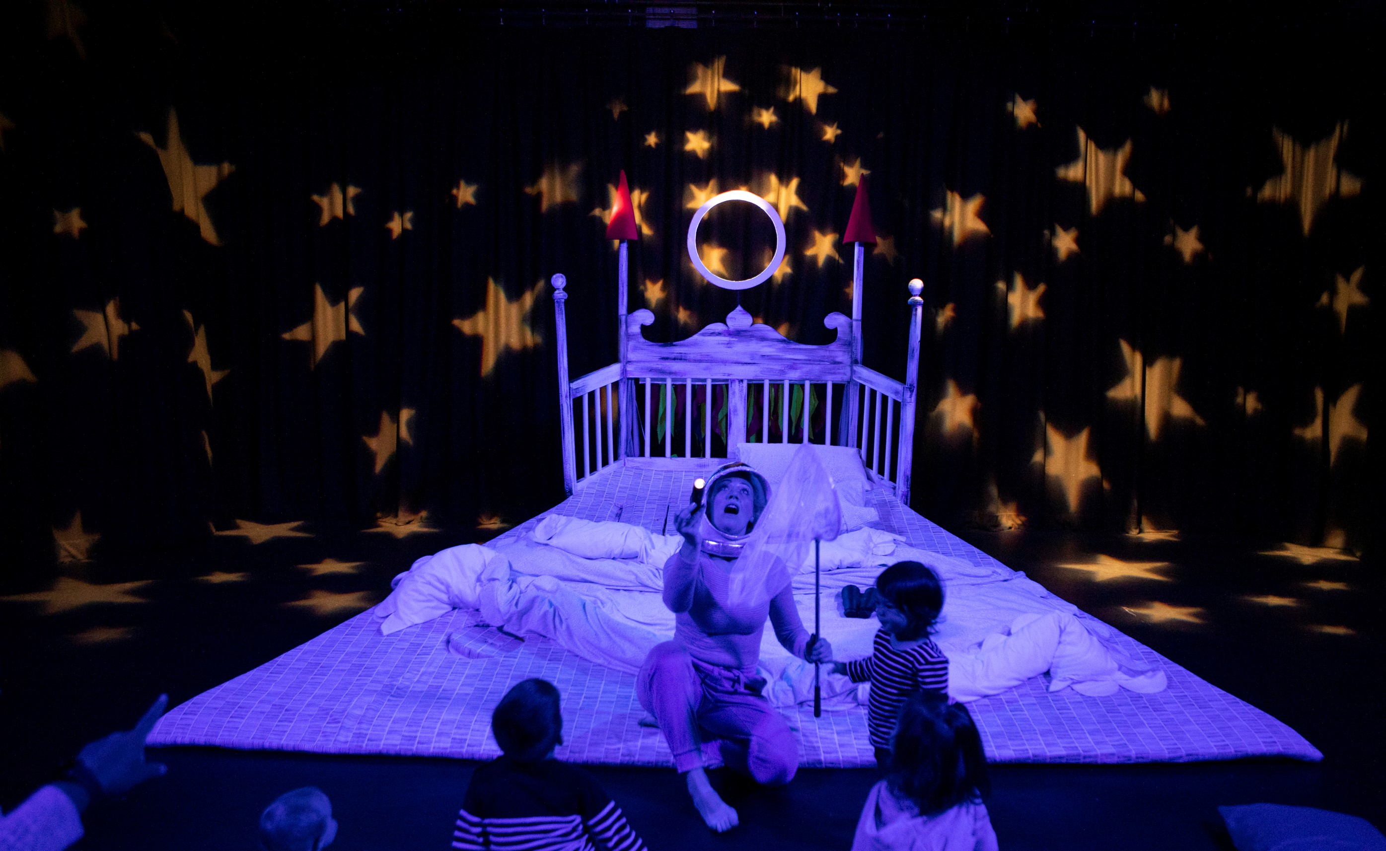 Whimsical children's event stage with starry projections and interactive performers.