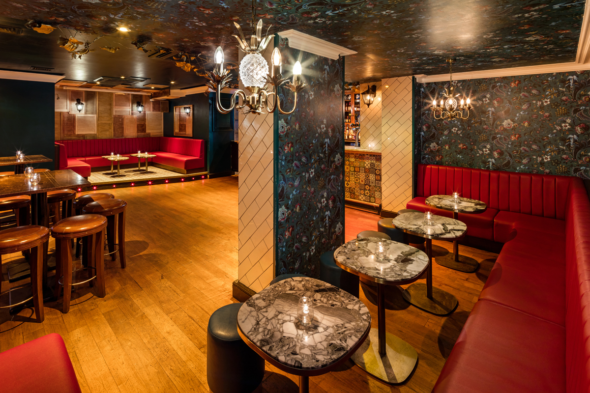 Stylish event space in Shoreditch with plush red seating and elegant marble tables.