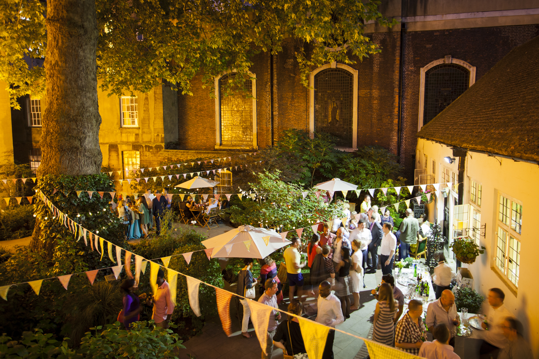 Vibrant outdoor event in The City Garden, featuring lush greenery and warm lighting.