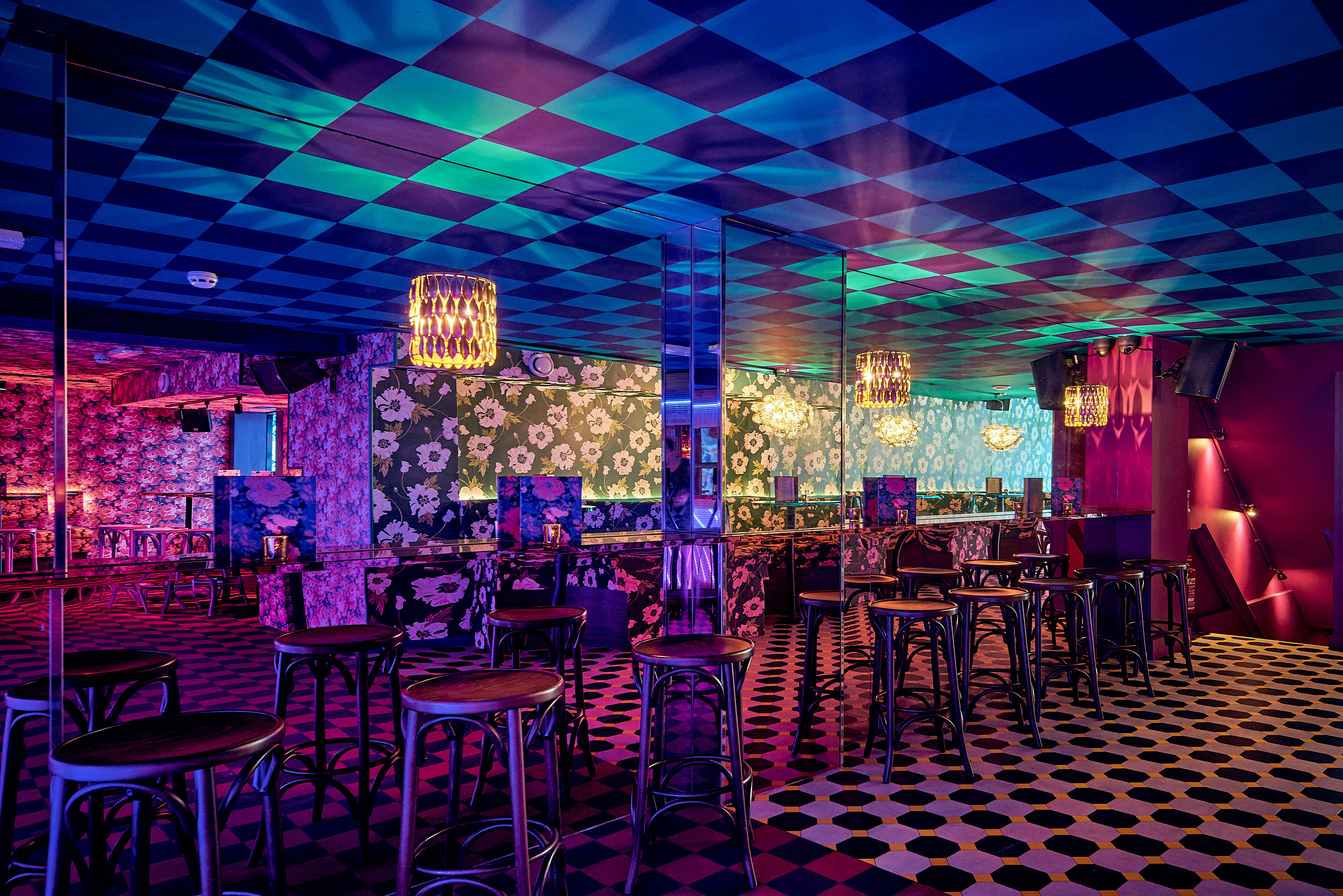 Vibrant event space at Blame Gloria with floral wallpaper, ideal for gatherings and parties.