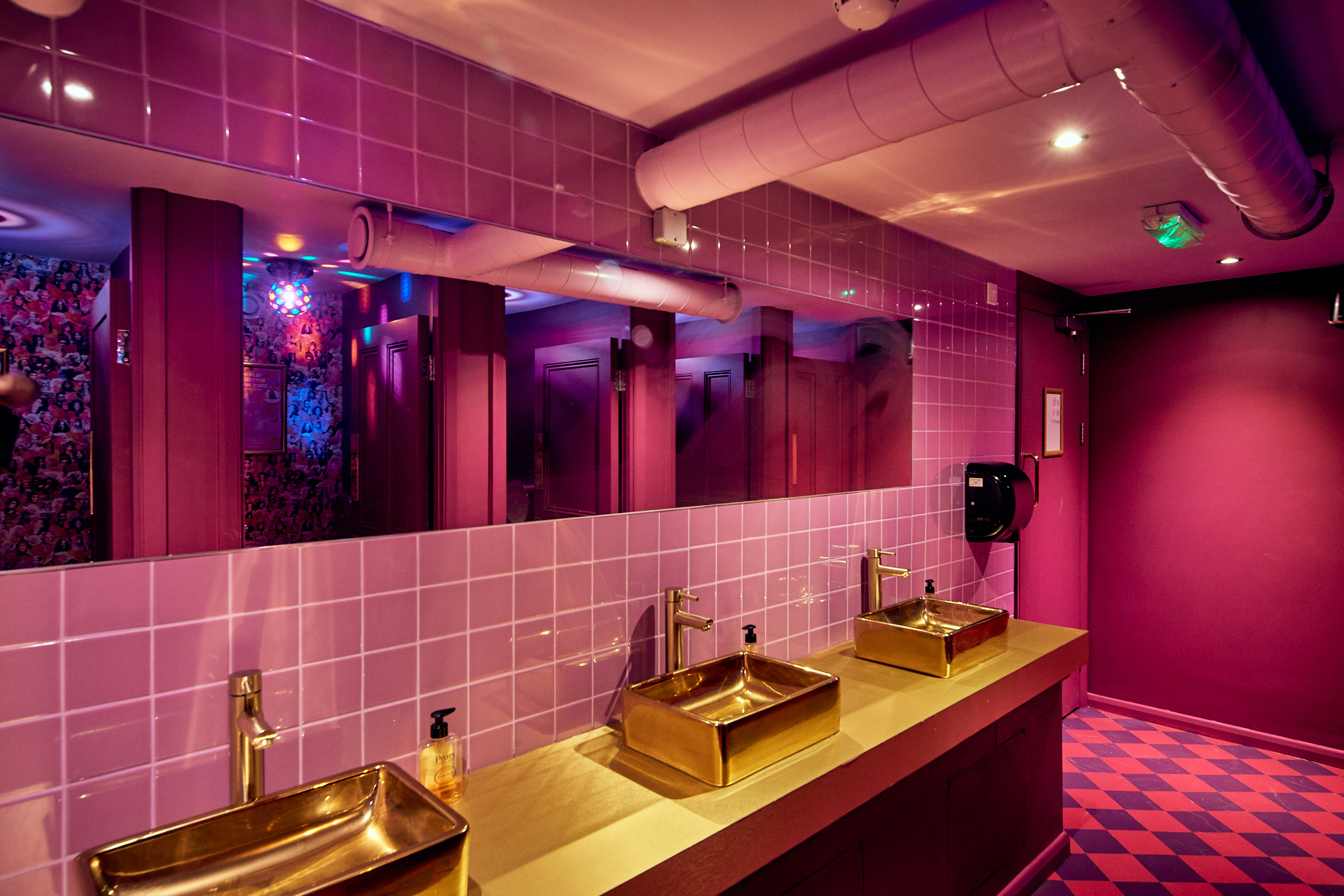 Vibrant restroom with gold sinks and purple tiles at Blame Gloria Clapham Junction event venue.