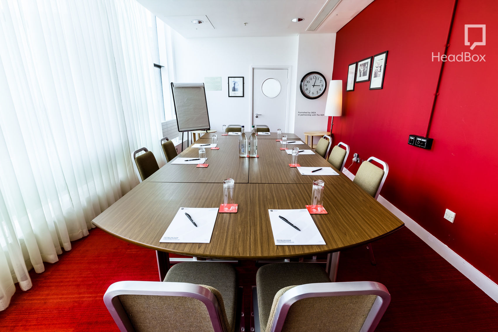 Meeting room at Unique Venues Birmingham with red accent wall, ideal for professional events.