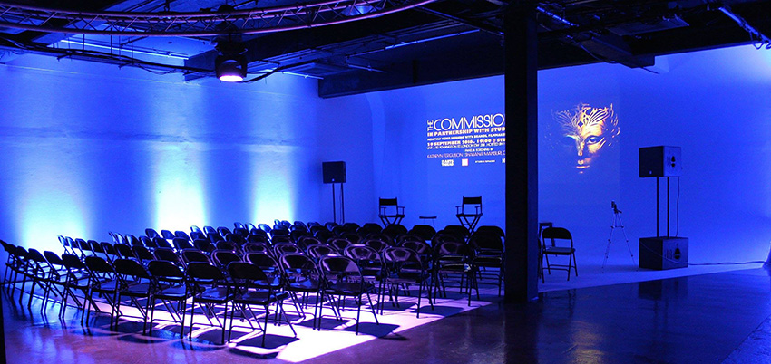 Modern event space with blue lighting, ready for a presentation or panel discussion.