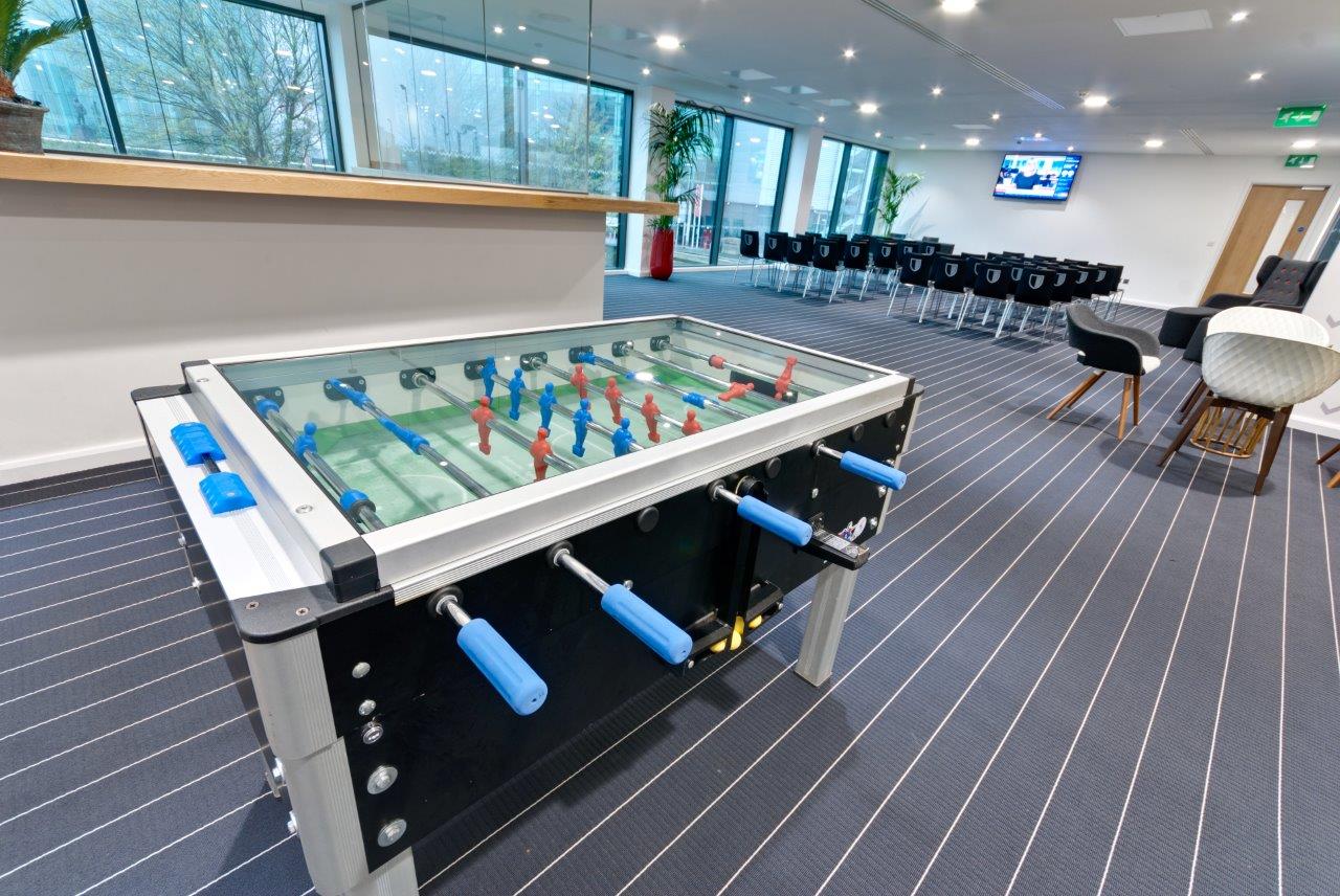 Modern meeting space with glass-top foosball table at Hotel Football for team engagement.