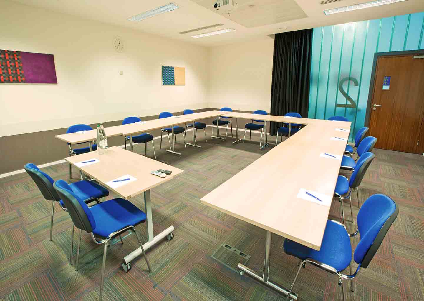 U-shaped meeting room with blue chairs at Imperial College for workshops and strategy sessions.
