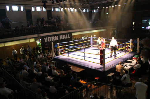 Vibrant boxing event at York Hall with a well-lit ring and energetic crowd.