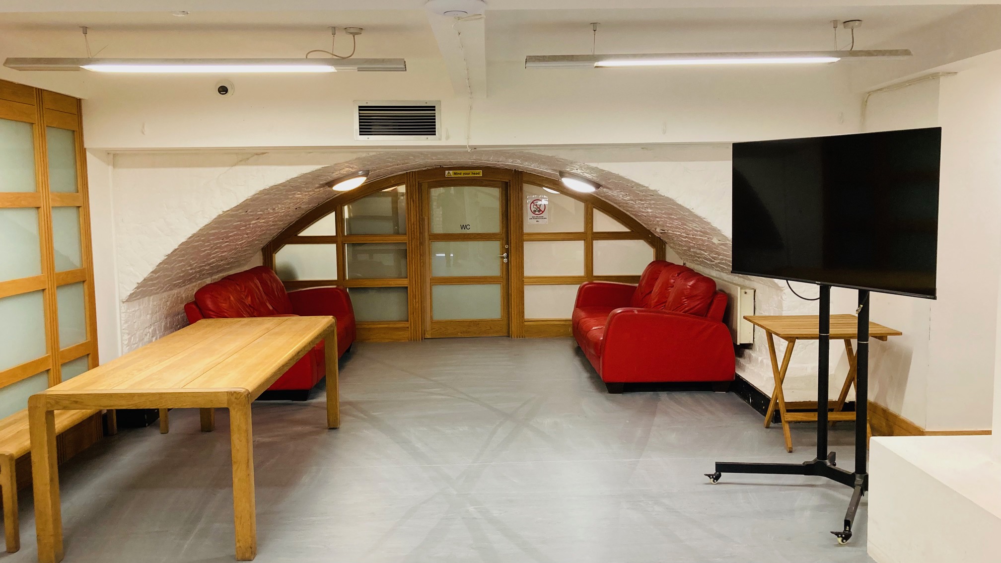 Cozy meeting space in Crypt, St John's Hoxton with red sofas and arched ceiling.